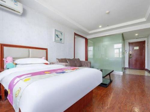 a bedroom with a large bed and a living room at GreenTree Inn Yinchuan Pedestrian Street East Liqun Street Express Hotel in Yinchuan