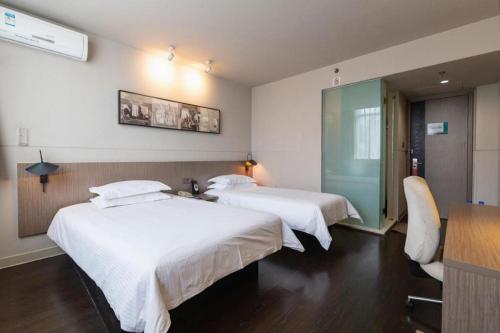 a hotel room with two beds and a glass wall at Jinjiang Inn Xi'an Zhonglou North Street Metro Station in Xi'an