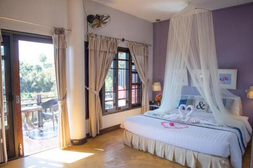 une chambre avec un lit blanc à baldaquin dans l'établissement Phumorkdao Resort, à Pong Yaeng