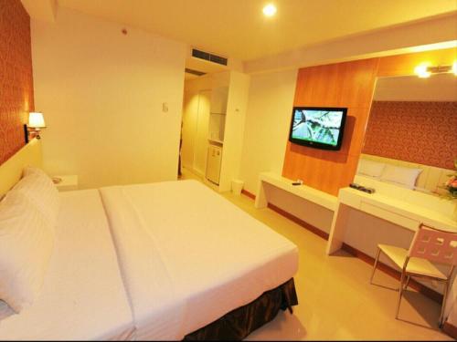 ein Hotelzimmer mit einem großen Bett und einem Fernseher in der Unterkunft Pratunam Hotel in Ban Si Than