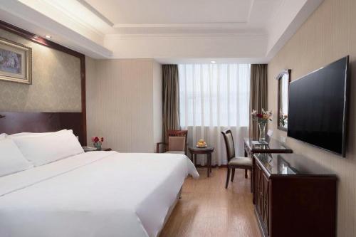 a hotel room with a large white bed and a desk at Vienna Hotel Shanxi Taiyuanfu West Street in Taiyuan