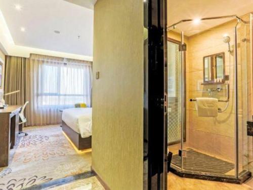 a hotel room with a bed and a shower at Lavande Hotel Tianjin Binhia Yujiabao Finance Center Branch in Binhai