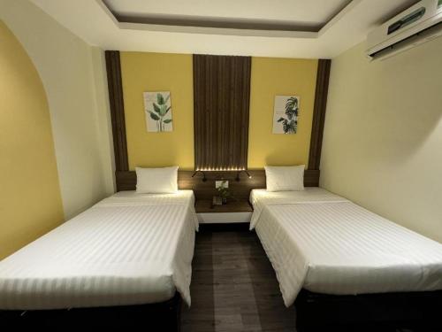 two beds in a room with yellow walls at La Phan Huy Ich Hotel in Ho Chi Minh City