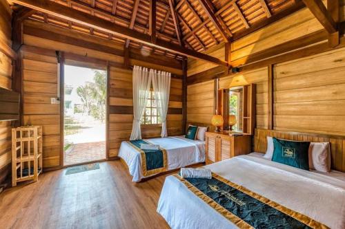 two beds in a room with wooden walls at HON BA LAGI BEACH RESORT in La Gi