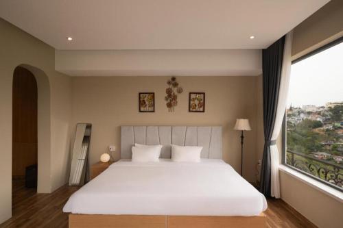 a bedroom with a large white bed and a large window at Gold View Boutique Hotel Đà Lạt in Da Lat