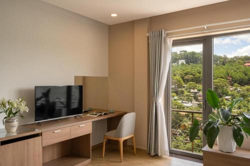 a room with a desk with a television and a window at Gold View Boutique Hotel Đà Lạt in Da Lat