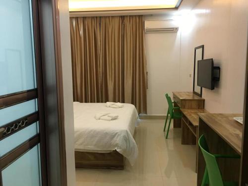 a room with a bed and a desk and a television at Hotel Primera in Zamboanga