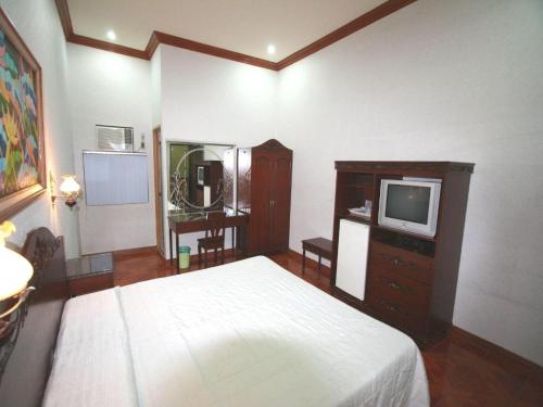 a bedroom with a bed and a tv in it at Pearlmont Hotel in Cagayan de Oro