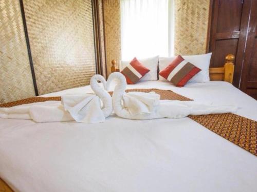 - deux serviettes de cygne sur un lit dans une chambre d'hôtel dans l'établissement Natura Maerim Resort, à Ban Nong Pla Man (1)