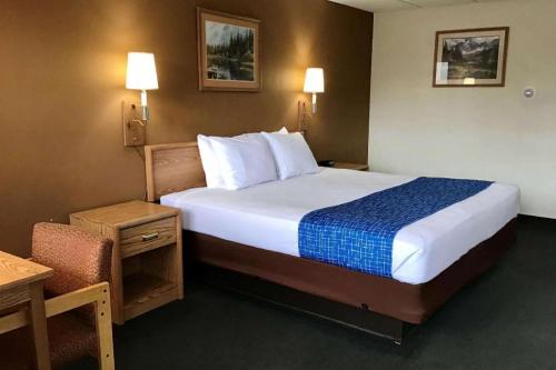 a hotel room with a large bed and a chair at Travelodge by Wyndham Powell in Powell
