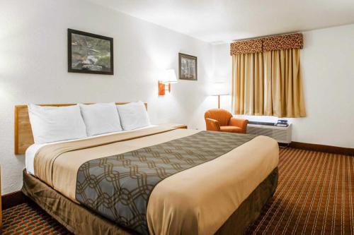 a hotel room with a large bed and a chair at Econo Lodge Truman Inn in Sedalia