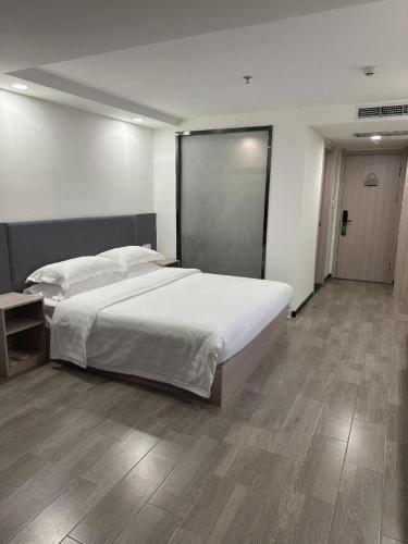 a bedroom with a large white bed and a wooden floor at Dalian Bohai Pearl Hotel in Dalian