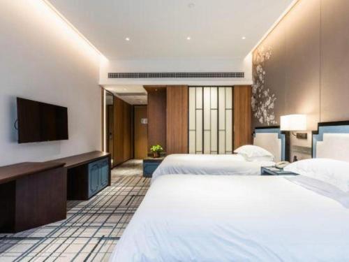 a hotel room with two beds and a flat screen tv at International Conference Hotel Nanjing in Nanjing