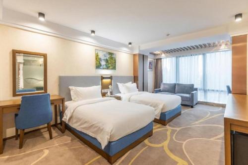 a hotel room with two beds and a desk at Dalian Bohai Pearl Hotel in Dalian