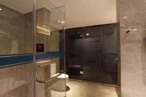 a bathroom with a toilet and a glass shower stall at Dalian Bohai Pearl Hotel in Dalian