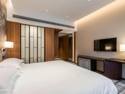 a bedroom with a large white bed and a television at International Conference Hotel Nanjing in Nanjing