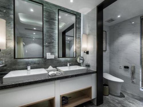 a bathroom with two sinks and a mirror and a tub at International Conference Hotel Nanjing in Nanjing