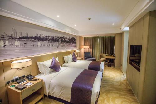 a hotel room with a large bed and a desk at Sky World Hotel Qingdao in Qingdao