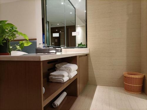 a bathroom with a sink and a mirror and towels at Da Peng Zhongzhou Hotel in Haikou