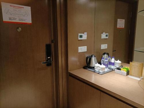 a room with a door and a counter with a coffee maker at Da Peng Zhongzhou Hotel in Haikou