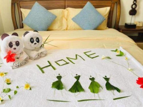 two stuffed pandas are sitting on a bed with flowers at Da Peng Zhongzhou Hotel in Haikou