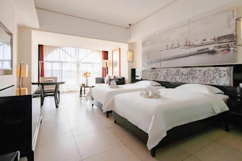 a hotel room with two beds and a dining area at Da Peng Zhongzhou Hotel in Haikou