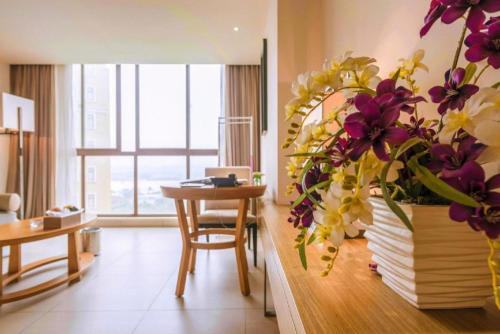 a living room with a table and a vase of flowers at Da Peng Zhongzhou Hotel in Haikou