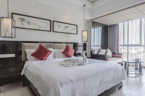 a bedroom with a large white bed with red pillows at Da Peng Zhongzhou Hotel in Haikou