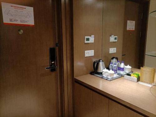 a room with a door and a counter with a coffee maker at Da Peng Zhongzhou Hotel in Haikou