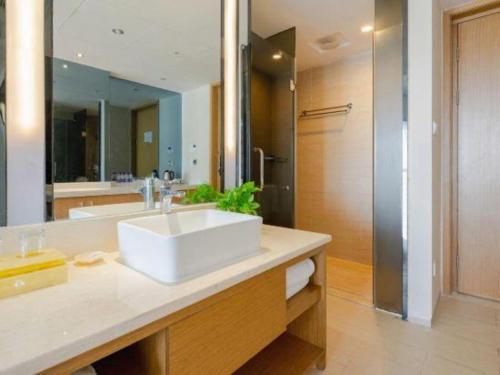 a bathroom with a white sink and a mirror at Da Peng Zhongzhou Hotel in Haikou