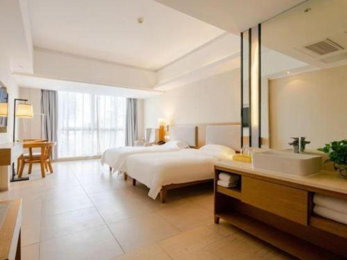a bedroom with a bed and a sink and a mirror at Da Peng Zhongzhou Hotel in Haikou