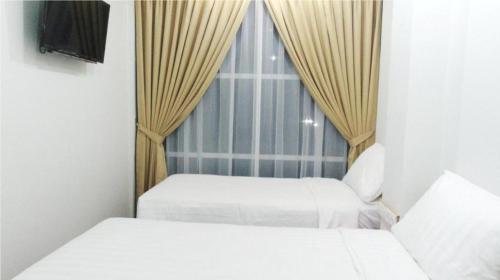 two beds in a small room with a window at An Hotel Jakarta in Jakarta