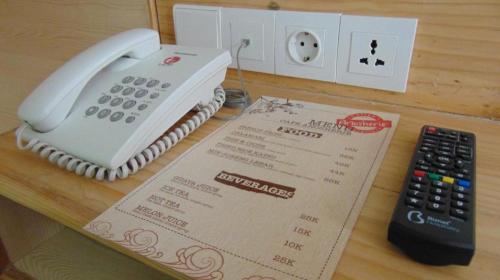 a telephone and a remote control sitting on a table at An Hotel Jakarta in Jakarta