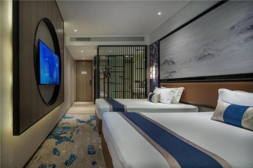 a hotel room with two beds and a tv at Yuan Culture Hotel Shenzhen World Shajing in Shenzhen