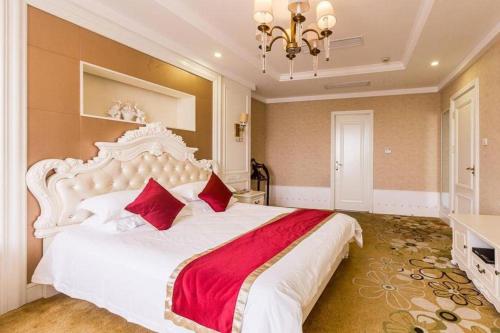 a bedroom with a large white bed with red pillows at New century Manju Select Hotel Hongqiao Hub National Exhibition Center in Shanghai