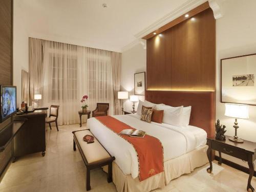 a hotel room with a large bed and a desk at Hotel Ammi Cepu in Cepu