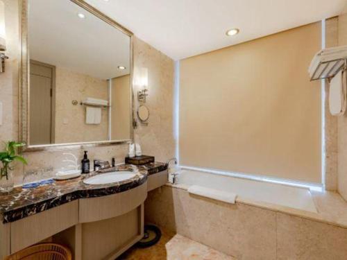 a bathroom with a tub and a sink and a mirror at Hefei Parkview Hotel in Hefei