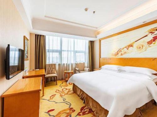 a hotel room with a large bed and a television at Vienna Classic Hotel Qingdao Huangdao in Huangdao