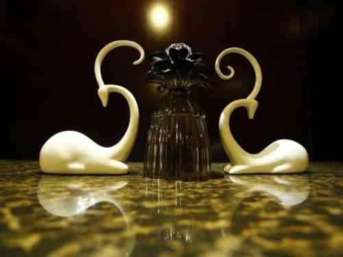 two white swans sitting on a table with a vase at Hefei Parkview Hotel in Hefei