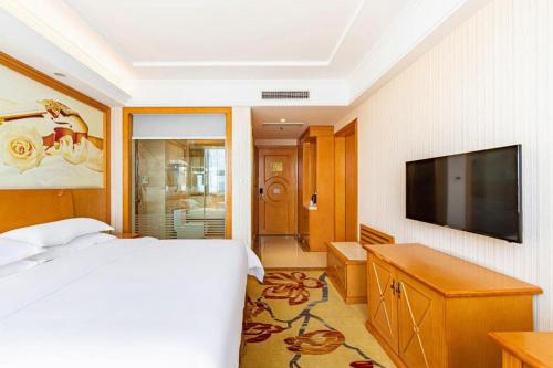 a bedroom with a bed and a flat screen tv at Vienna Classic Hotel Qingdao Huangdao in Huangdao