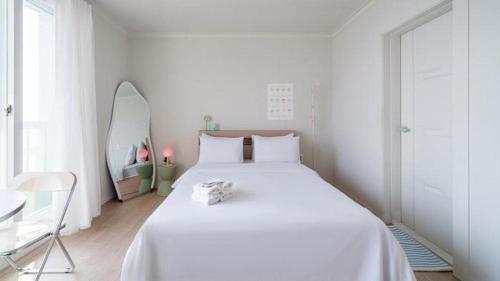 a white bedroom with a large white bed and a table at Gallery Pension in Taean