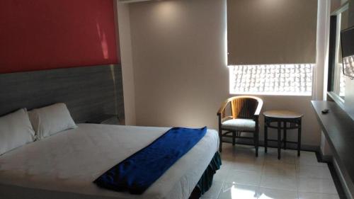 a bedroom with a bed and a window and a chair at Kharisma Hotel in Madiun