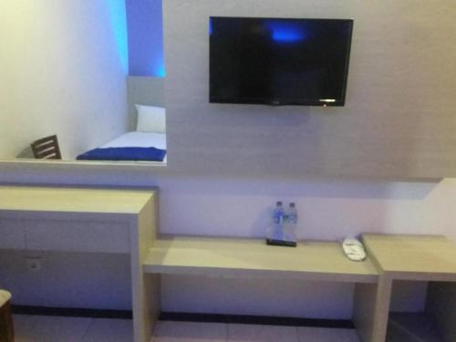 a room with a desk with a tv on the wall at Kharisma Hotel in Madiun