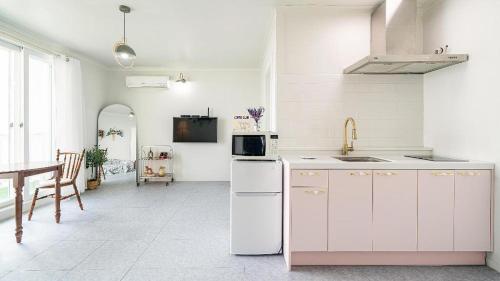 a white kitchen with a sink and a refrigerator at Gallery Pension in Taean