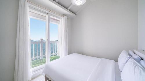a bedroom with a white bed and a large window at Gallery Pension in Taean