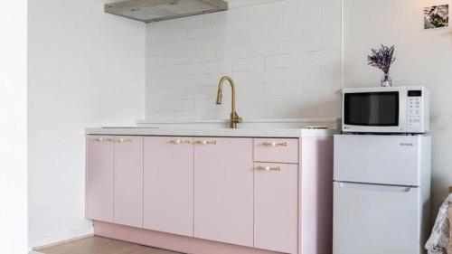 a kitchen with a sink and a microwave and a refrigerator at Gallery Pension in Taean