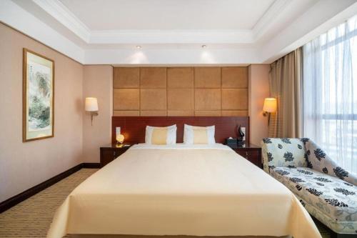 a hotel room with a large bed and a chair at Chinflux Mandarin Hotel in Dongguan