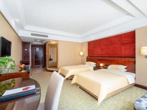 a hotel room with two beds and a table at Chinflux Mandarin Hotel in Dongguan