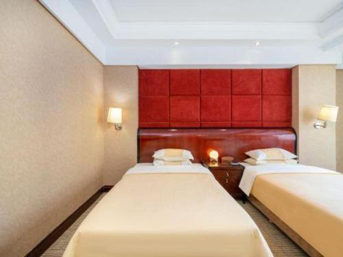 a room with two beds and a red wall at Chinflux Mandarin Hotel in Dongguan