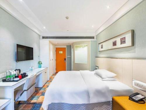 a bedroom with a large white bed and a television at Zaozhuang Hotel in Zaozhuang